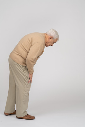 Side view of an old man in casual clothes bending down