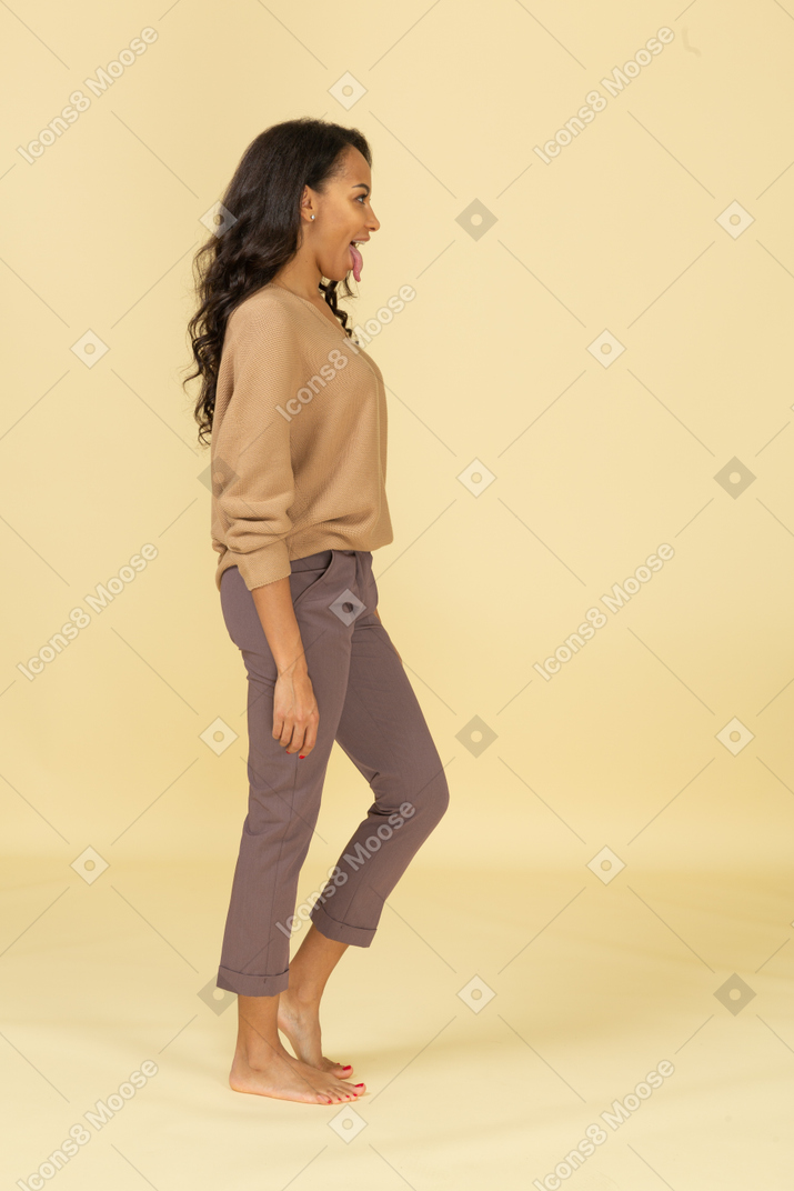 Side view of a young female in casual clothes showing tongue