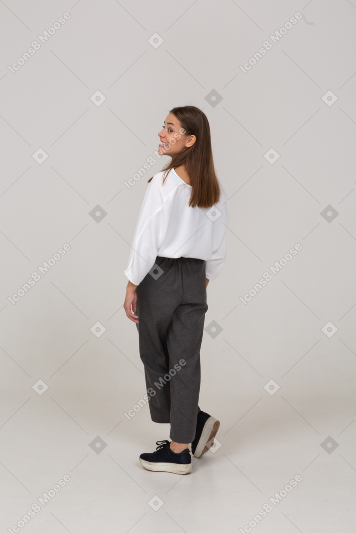 Vista posteriore di tre quarti di una giovane donna in abiti da ufficio che sorride