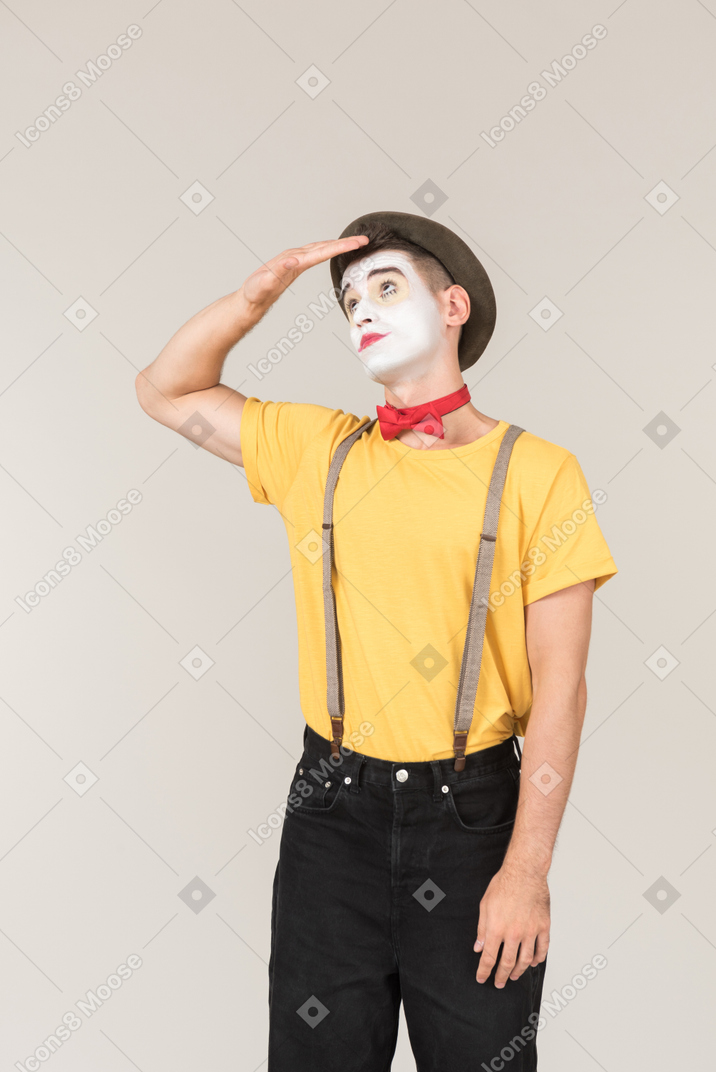 Dreamy male clown holding hand next to his forehead and looking up