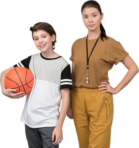 Profesora de pe y su alumno sosteniendo una pelota de baloncesto