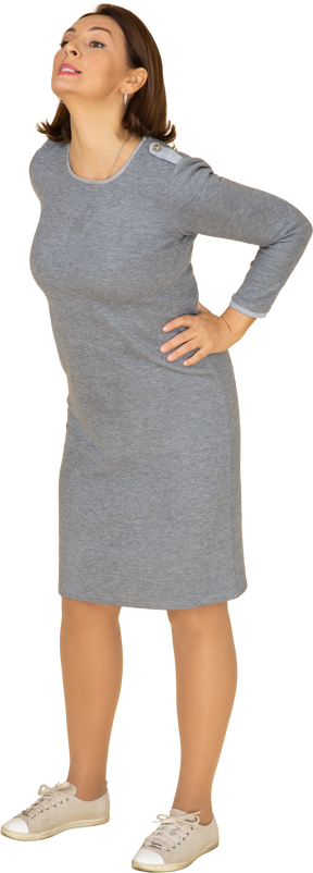 Vue latérale d'une femme en robe grise debout avec les mains sur les hanches