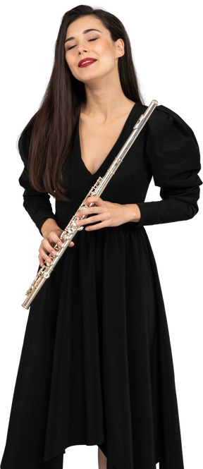 Вид спереди молодой леди в черном платье, держащей флейту