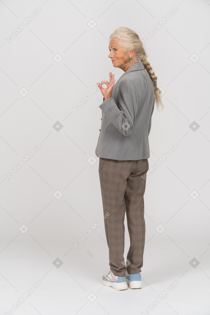 Retrovisor de uma senhora idosa de terno mostrando sinal de ok