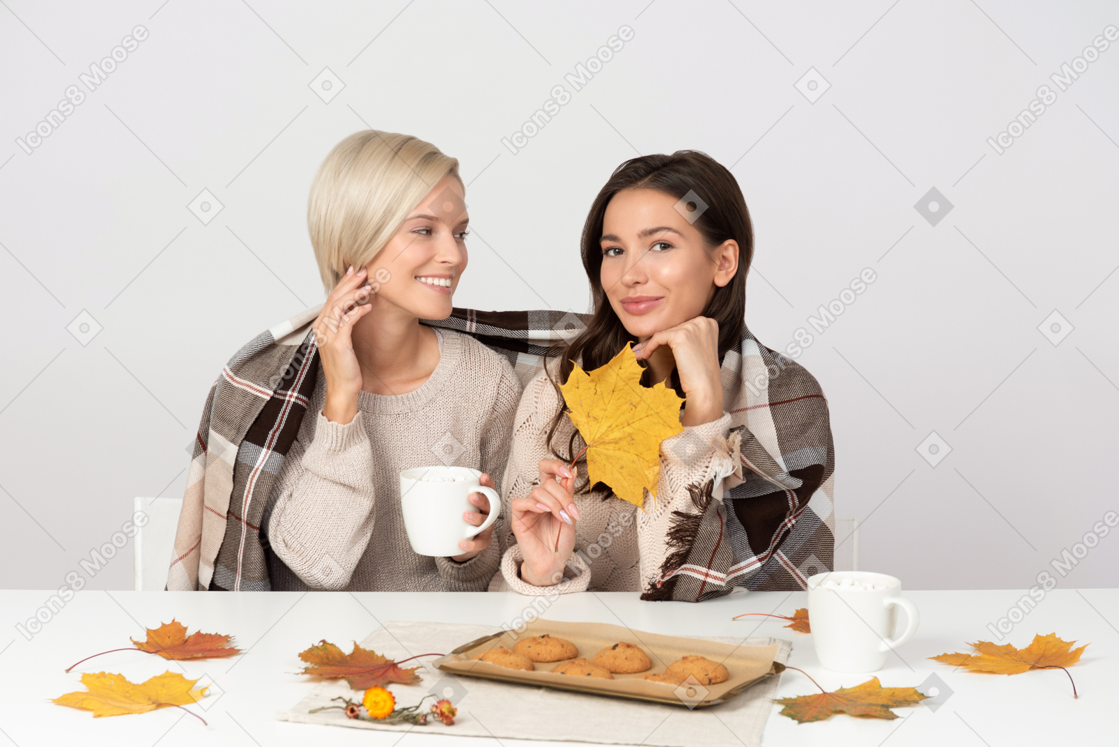 Young women drinking coffee and eating cookies in autumn