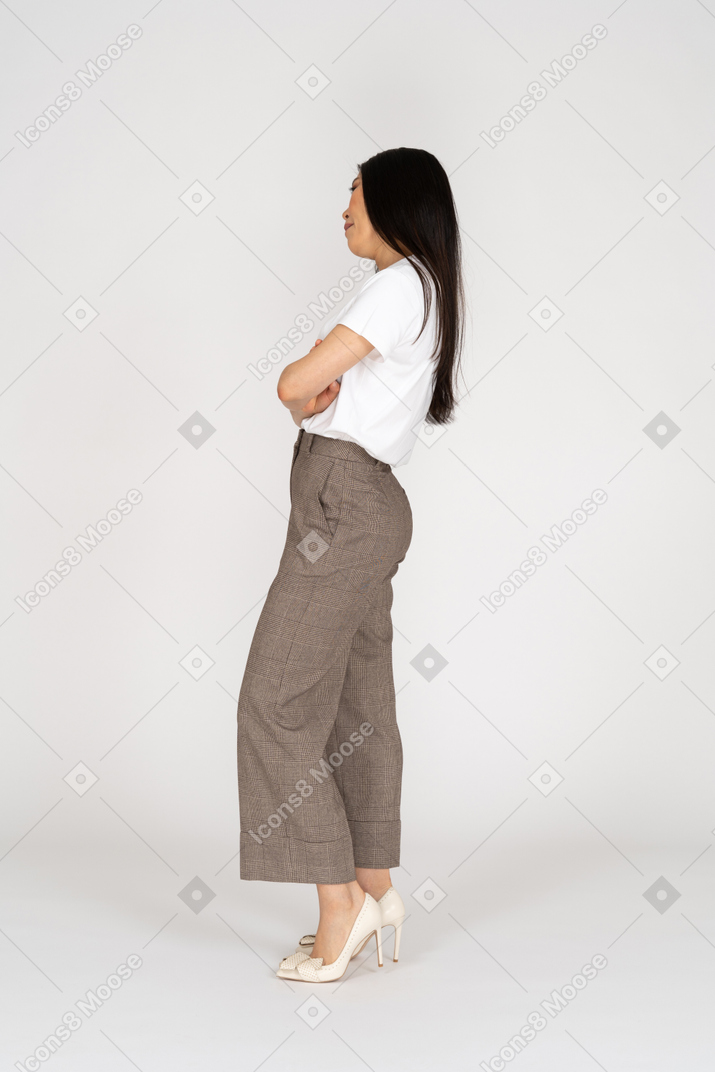 无聊的年轻女子，在马裤和t恤交叉手和倾斜头的侧视图