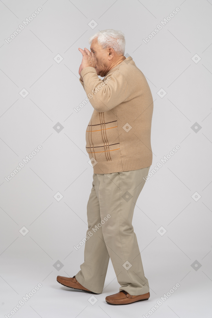 Side view of an old man in casual clothes scaring someone