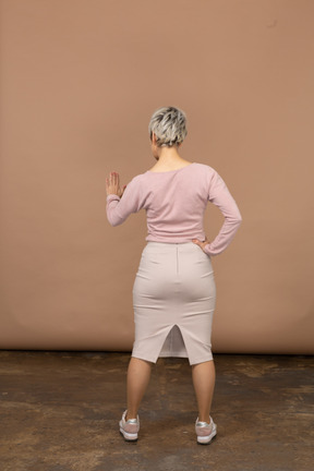Вид сзади женщины в повседневной одежде, показывающей жест стоп