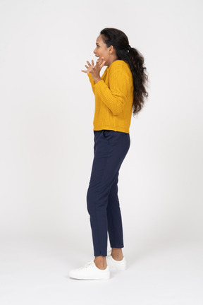 Side view of a happy girl in casual clothes gesturing