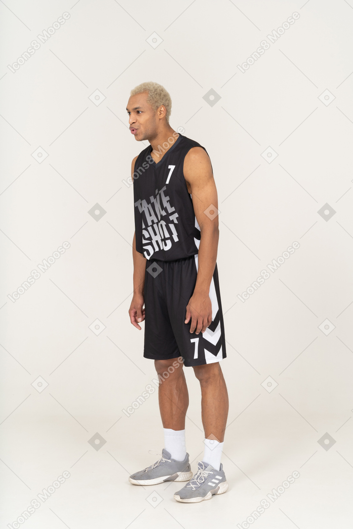 Three-quarter view of a whistling young male basketball player leaning forward
