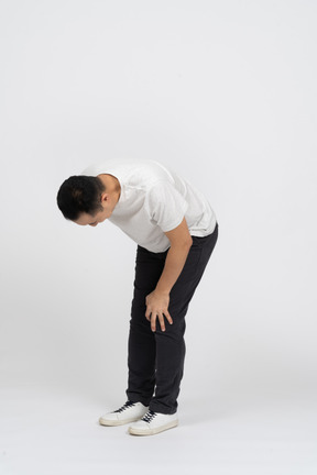 Front view of a man bending down and touching hurting knee