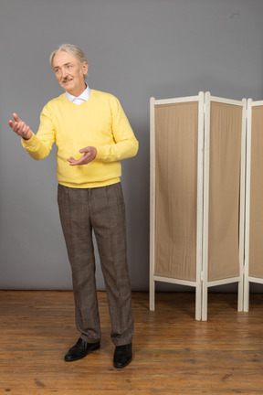 Vue de trois quarts d'un vieil homme souriant expliquant quelque chose en gesticulant