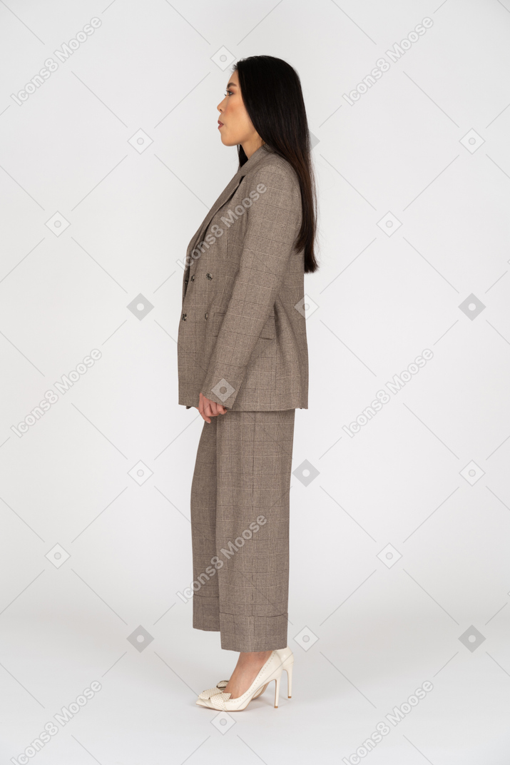 Vue latérale d'une jeune femme en costume brun à la recherche de côté