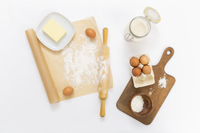 Planche à découper avec de la farine sur une assiette, des pommes et des œufs