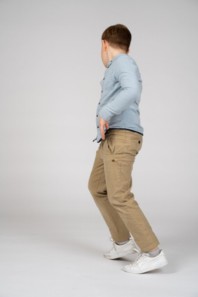 A boy in a blue shirt and khaki pants running away