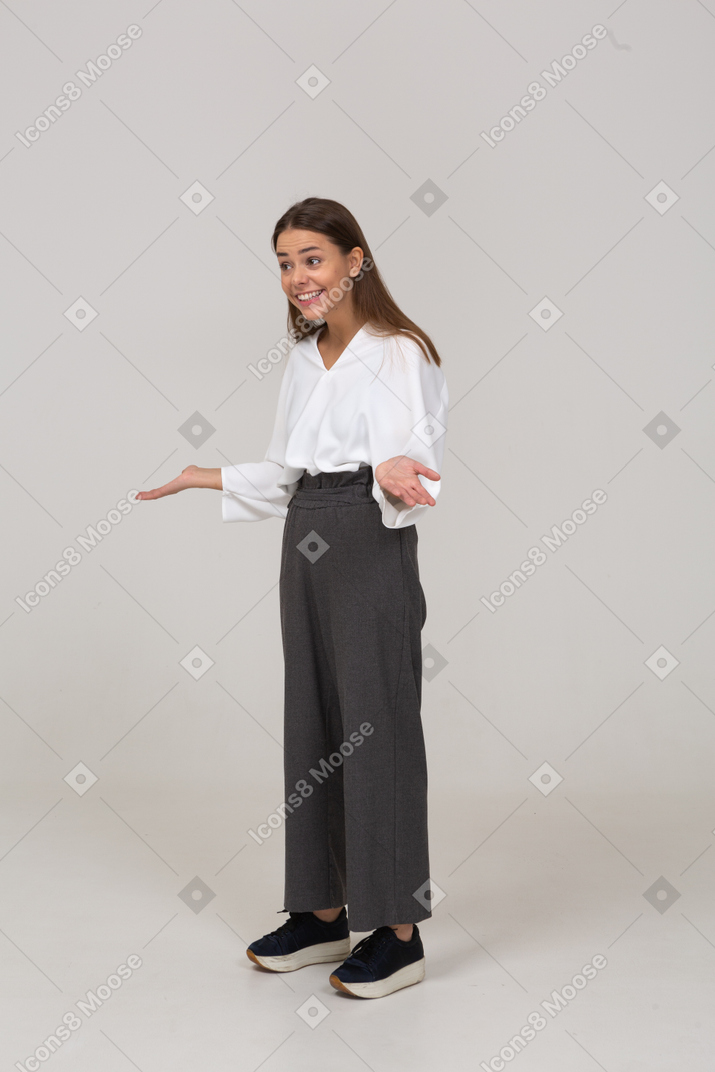 Vista di tre quarti di una giovane donna sorridente in abiti da ufficio che allarga le mani