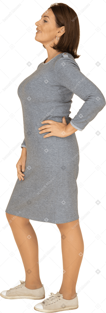 一个穿着灰色连衣裙的女人的侧视图，手放在臀部