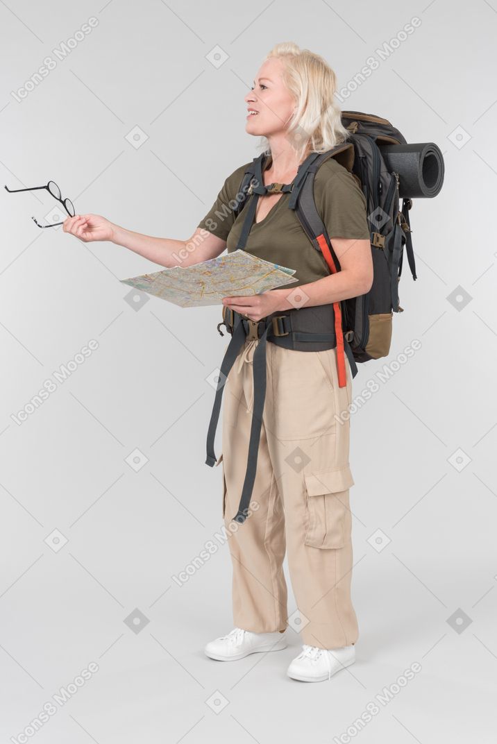 Female mature tourist carrying backpack and holding travel map