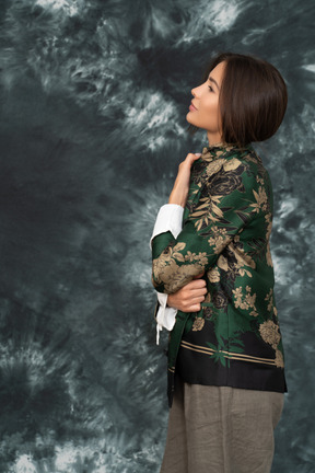 Retrato lateral de mujer joven sosteniendo su chaqueta de seda