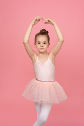 Menina vestindo um tutu e em pé na posição de balé