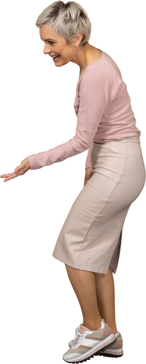 Vista laterale di una donna felice in abiti casual che mostra un gesto di benvenuto