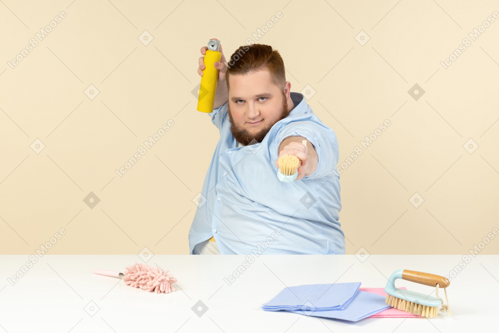 과체중인 젊은 남자가 탁자에 앉아 청소 장비를 들고 있다