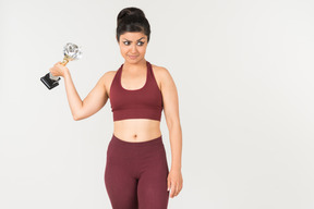 Serious looking young indian woman in sporstwear holding award