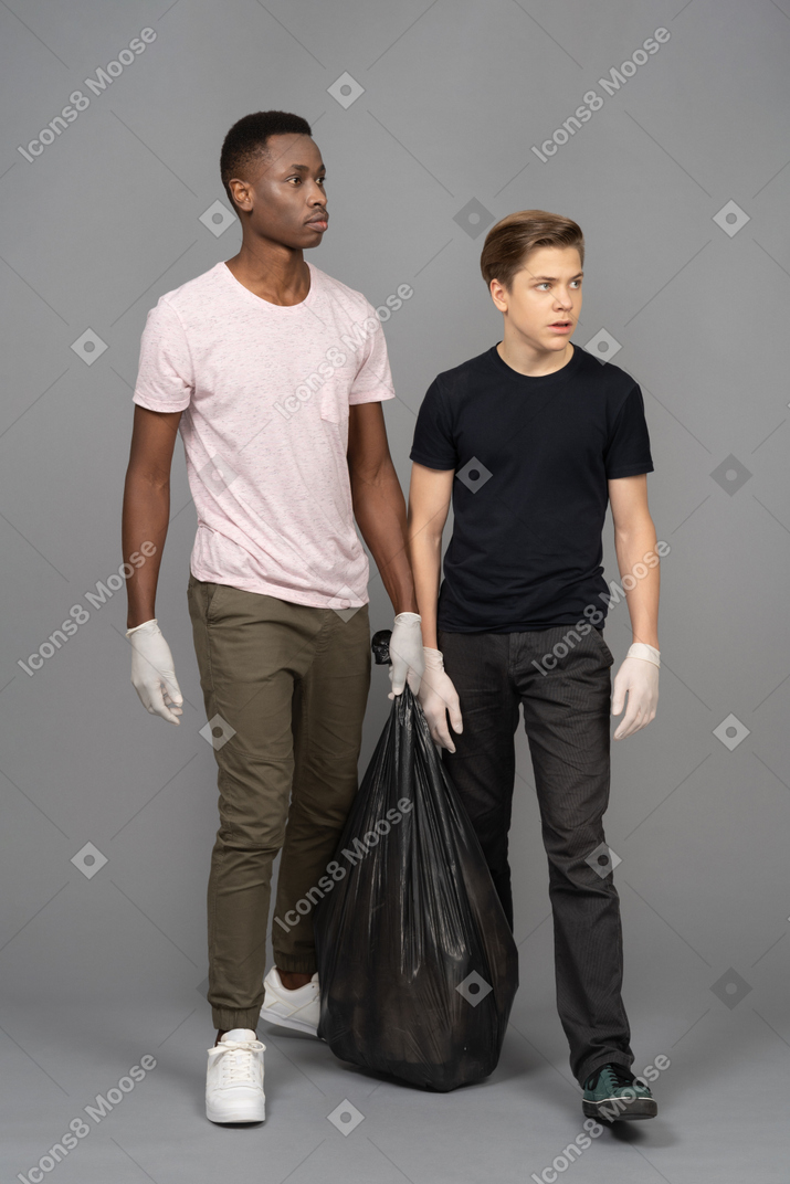 两个年轻人提着垃圾袋