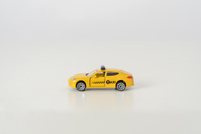 Yellow toy car photographed in profile on grey background