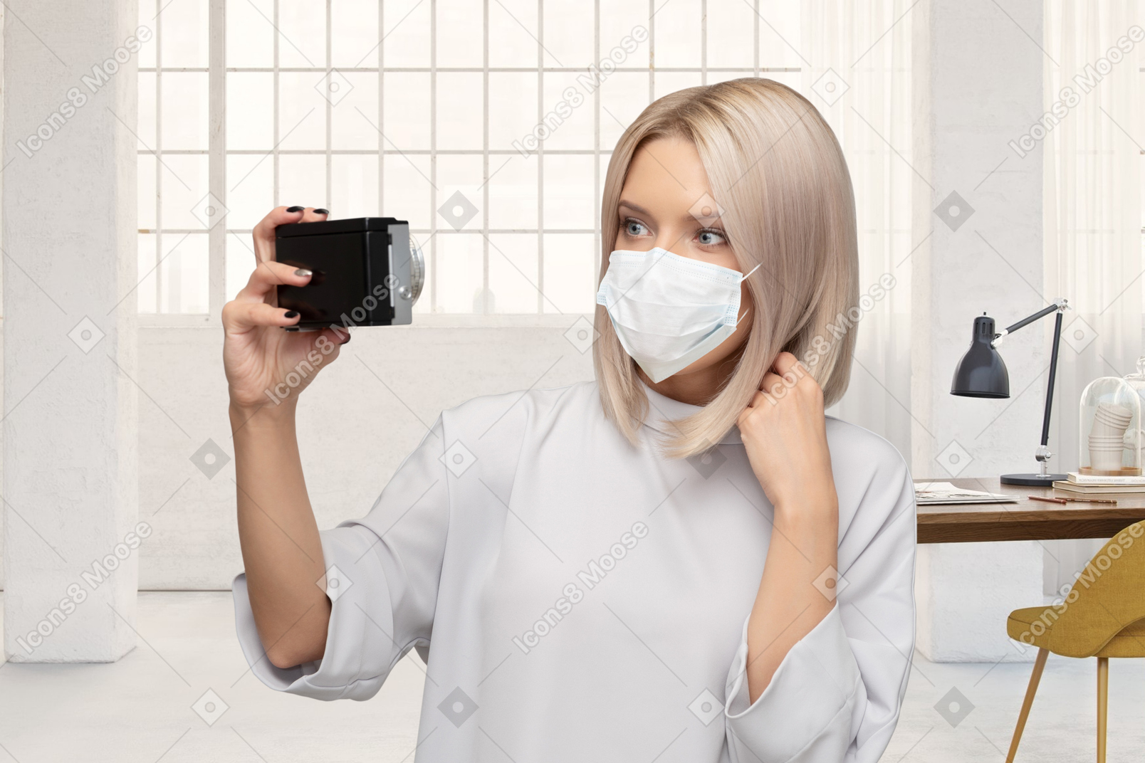 A woman wearing a face mask taking selfie on camera