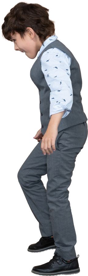 Vista lateral de un niño con traje gris caminando