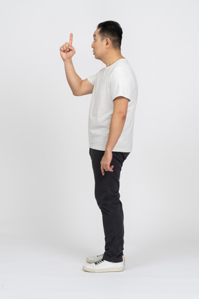 Side view of a man in casual clothes pointing up