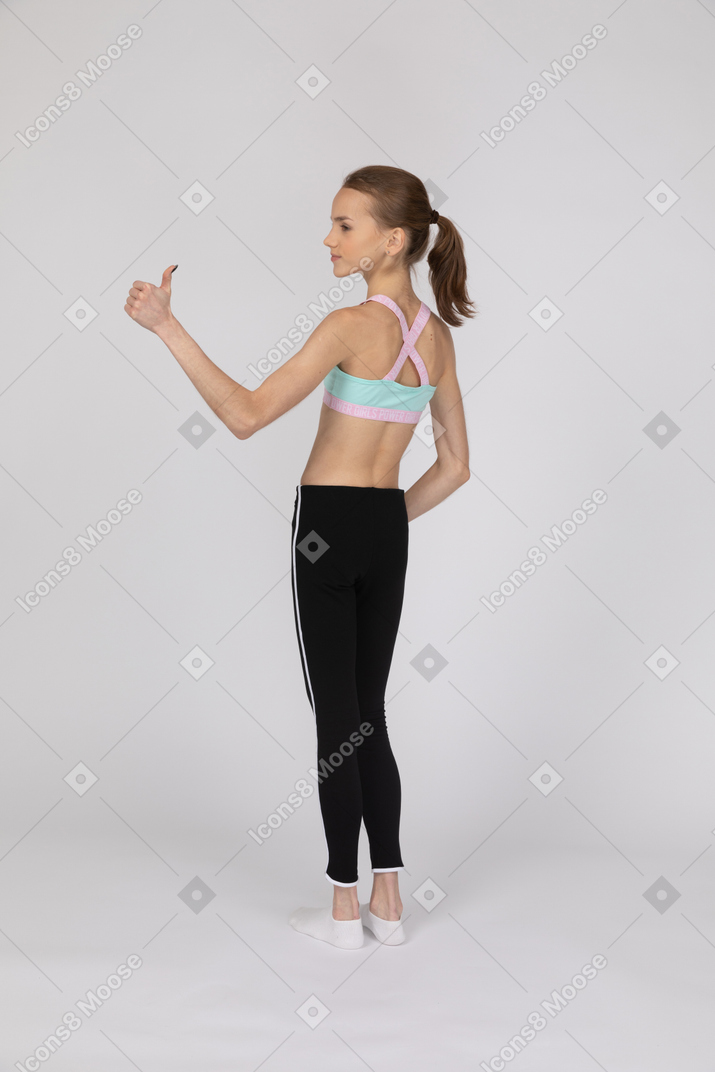 Vista posterior de una adolescente mostrando el pulgar hacia arriba
