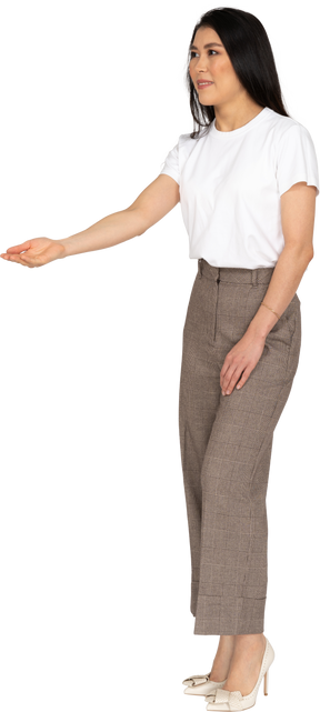 Vista de tres cuartos de una joven en pantalones y camiseta extendiendo su mano