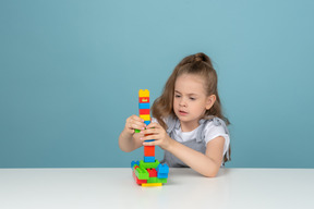 Bambina che costruisce una torre con i blocchi di lego