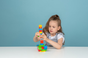 Menina construindo uma torre com blocos de lego