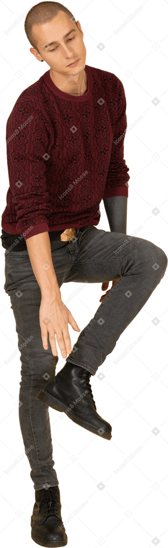 Vista di tre quarti di un giovane stanco in pullover rosso che si tocca la caviglia