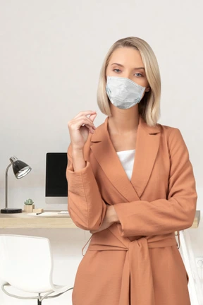 A woman wearing a face mask standing in front of a desk