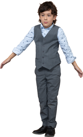 Vista frontale di un ragazzo in abito grigio in piedi con le braccia tese