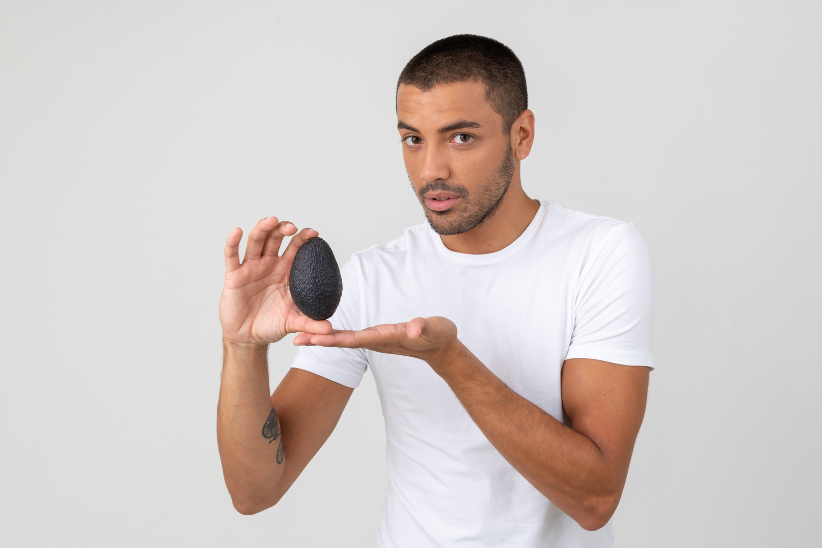 Young man in a white t-shirt holding an avocado