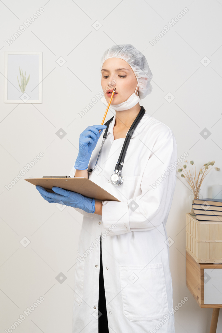 Three-quarter view of a puzzled young female doctor making notes on her tablet