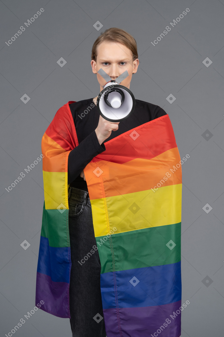 Person wrapped in rainbow flag holding megaphone