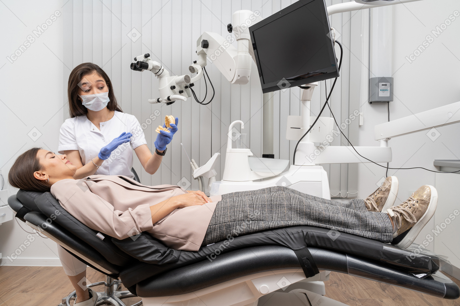 병원 캐비닛에서 여성 환자에게 치아 프로토 타입을 보여주는 여성 치과 의사의 전체 길이