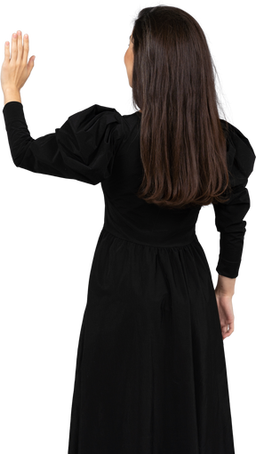 Vista traseira de uma jovem em um vestido preto levantando a mão