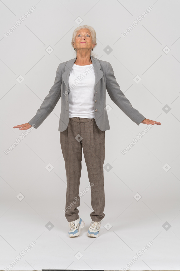 Front view of an old lady in suit standing on toes and outspreading arms