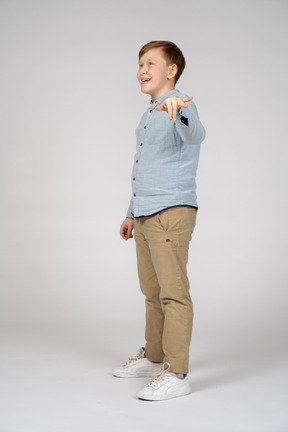 A young boy in a blue shirt pointing at something