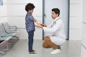 A doctor bandaging a little boy's arm