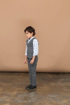 Cute boy in grey suit standing in profile