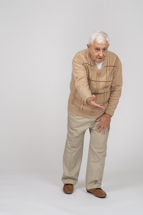 Vista frontale di un uomo anziano in abiti casual che fa un gesto di benvenuto
