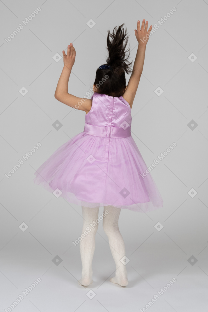 Vista trasera de una chica con vestido rosa saludando